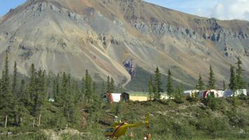 Image of helicopter landing in camp with mountain in background