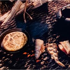 Image of bannock and fish cooking on fire